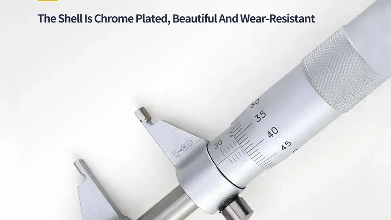 Close-up of a chrome-plated micrometer with the spindle and scale visible.